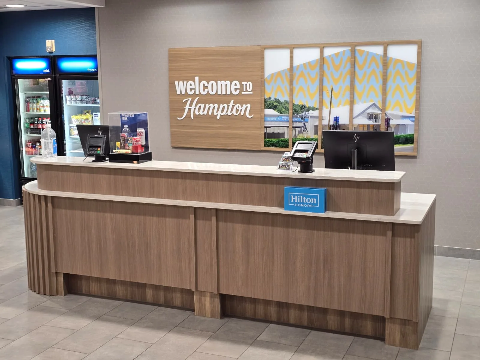 Front view of a two-level reception counter with wood-toned panels and light-colored tops.