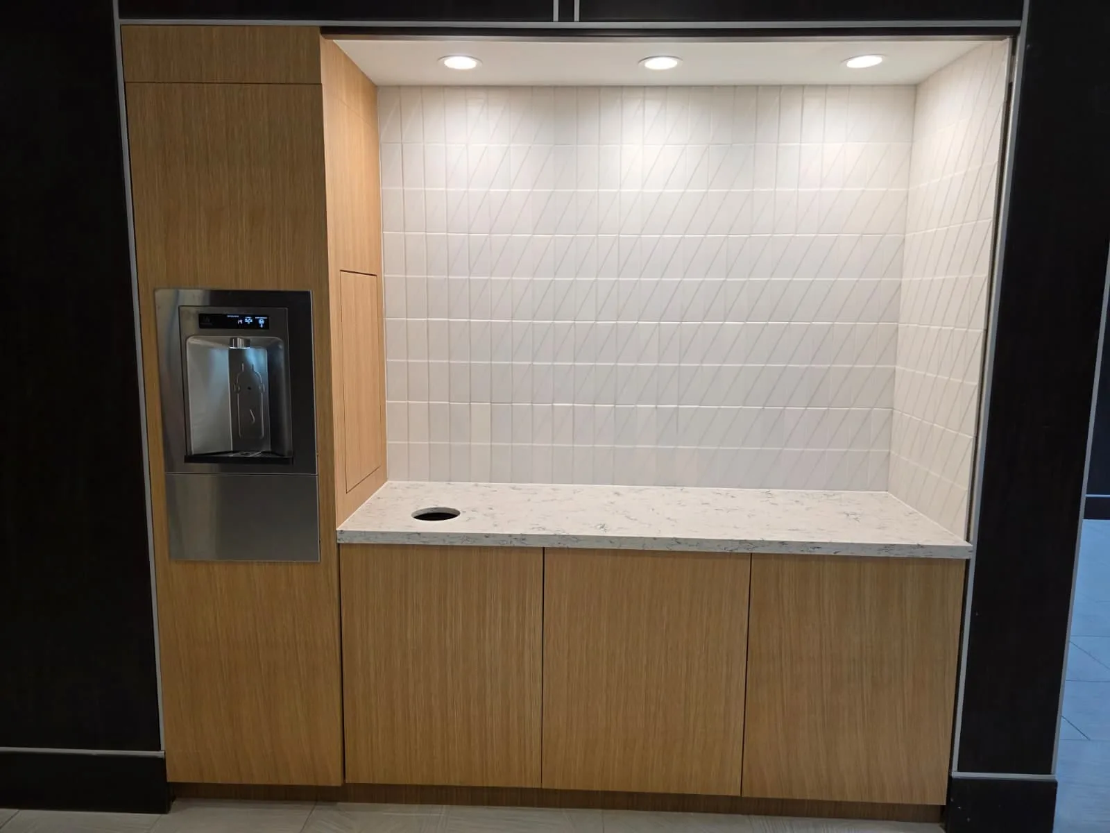 Wood-front hydration station with a bottle filler, recessed counter and lower cabinet doors