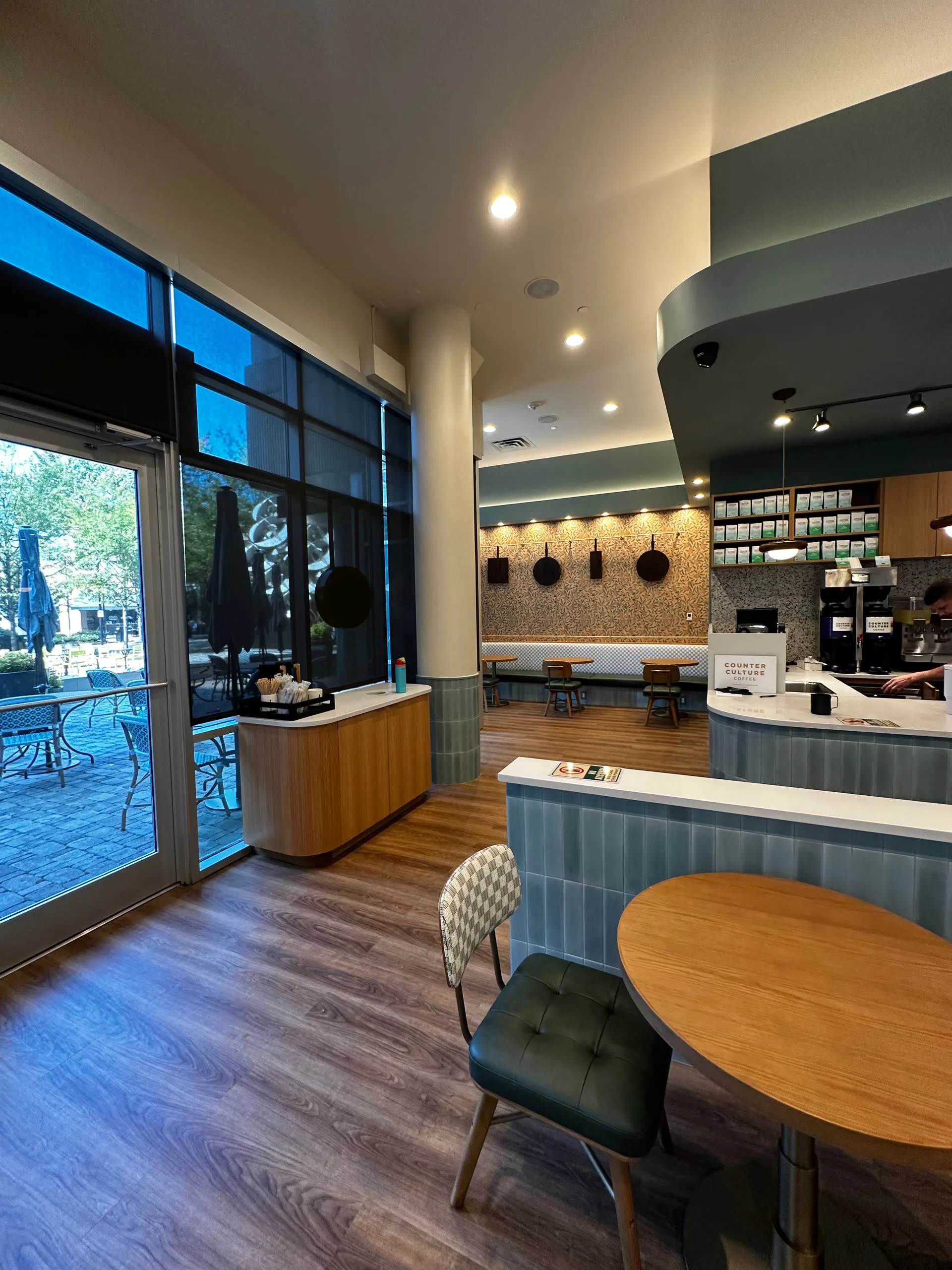 Meeting Grounds cafe entrance beside a rounded wood host stand, blue-tiled service counter and seating